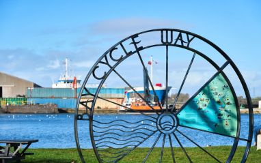 Bay Cycle Way marker at Glasson Dock with ship in background Wildey Media